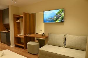 a living room with a couch and a tv on the wall at Prima Garden Residence in Durrës