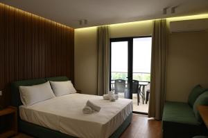 a bedroom with a bed and a balcony with a table at Prima Garden Residence in Durrës +68 photos