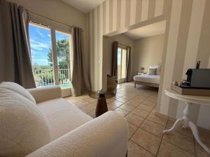 a living room with a white couch and a window at CÉRÈS - Boutique-Hôtel & Spa - Élégance en Terre d'Uzès in Saint-Quentin-la-Poterie