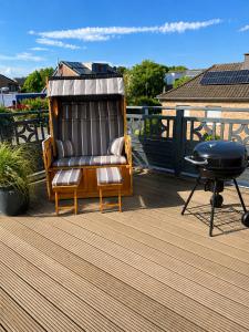 a chair sitting on a deck with a grill at FeWo Auszeit eigene große Terrasse mit Strandkorb und Grill in Wesel
