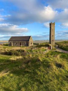 an old building and a tower in a field at Coastal Skylight Studio in Bettystown