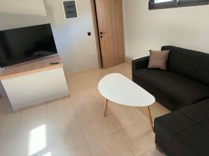 a living room with a black couch and a white stool at PETROKALIVa in Galatás