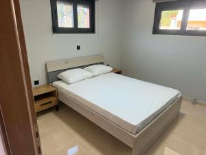 a small bedroom with a bed and two windows at PETROKALIVa in Galatás