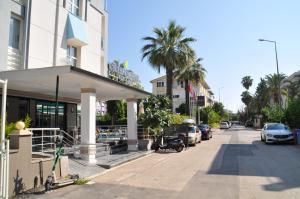 a building on a street with palm trees and cars at Citrus Urban Hotel in Antalya
