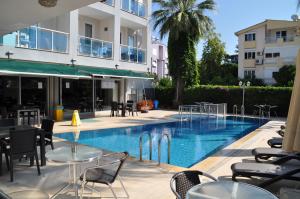 a swimming pool with tables and chairs next to a building at Citrus Urban Hotel in Antalya +13 photos