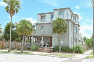 a white house with palm trees in front of it at The Mansard House in Galveston