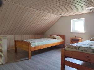 two beds in a room with a wooden ceiling at Domki Pod Kasztanem in Dąbki