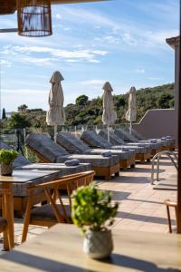 a row of tables and chairs with umbrellas on a roof at Skiathos Avaton Suites & Villas, Philian Hotels and Resorts in Megali Ammos