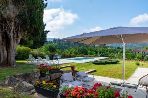 a patio with an umbrella and chairs and a pool at o fogar do cipres in Rivela