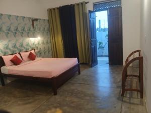 a bedroom with a bed and a chair and a door at Kentz villa in Arugam Bay