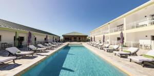 a pool with chaise lounge chairs next to a hotel at Ocean Breeze Resort in NCA