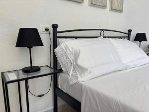 a bed with white sheets and a table with a lamp at Kambi rooms in Himare