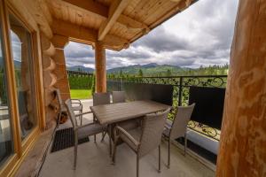 a patio with a wooden table and chairs on a balcony at Osada Małe Ciche DOMEK z Bali in Małe Ciche