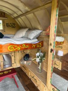 a room with a bed and a table with a vase of flowers at Vardo gypsy wagon in Berwick Saint John