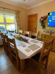 a dining room with a table with chairs and a television at Roskeen house in Tierna