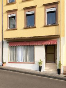 a yellow building with windows and two potted plants at Studio Kyllburg-Eifel in Kyllburg