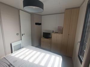 a small bedroom with a bed and a television at Cottage haut de gamme, tout confort in Agde