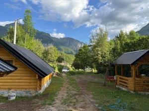 a cabin and a barn with mountains in the background at Bungalow-Guest House Alpina in Vusanje