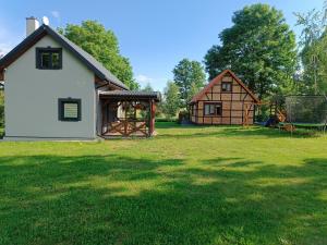 a large yard with a house and a playground at Jesionowy Zakątek domki z balią blisko jeziora in Piasutno