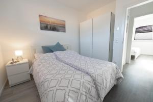 a white bedroom with a bed and a night stand at Sonne & Sand Strandnahes Ferienhaus mit Whirlpool, Sauna & Wallbox in Büsum