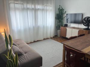 a living room with a couch and a flat screen tv at Apartamento Brisa Do Mar em Peruíbe in Peruíbe