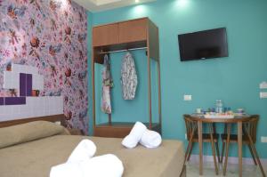 a room with two beds and a table and a tv at Adua Rooms - Tropea Center in Tropea