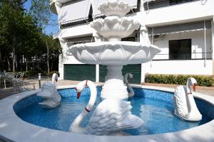 a fountain with swans in a pool in front of a building at Prima Garden Residence in Durrës
