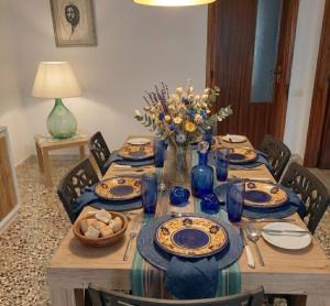 a table with blue plates and a vase of flowers at Simohouse Lecce - Executive Suite Apartment 140mq - 2 Bathrooms in Lecce