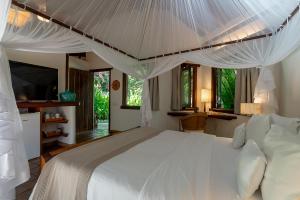 a bedroom with a large white bed with mosquito nets at Hotel e Resort Villas de Trancoso in Trancoso +191 photos