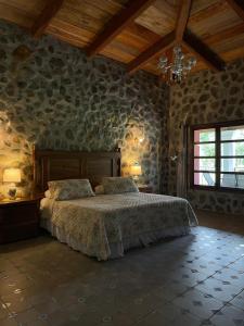 a bedroom with a bed in a room with stone walls at Hotel Boutique El Rosario in Teapa