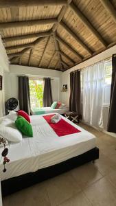 a bedroom with a large bed with red and green pillows at Hotel Miramar Capurganá Casa de playa in Capurganá