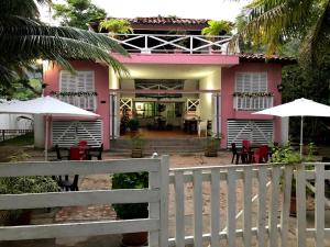 a pink house with a white fence and tables and umbrellas at Hotel Miramar Capurganá Casa de playa in Capurganá