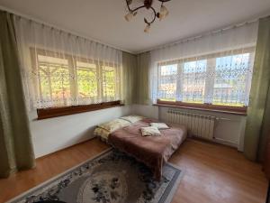 a small bedroom with a bed and two windows at Spokojna Zagroda in Biały Dunajec