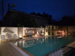 a swimming pool at night with chairs and umbrellas at Kaya Telavi in Telavi +19 photos