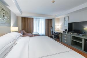 a hotel room with a large bed and a television at Barcelo Guadalajara in Guadalajara