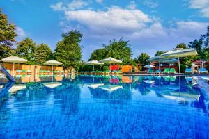 a large swimming pool with blue water and umbrellas at Q Hotel in Neptun