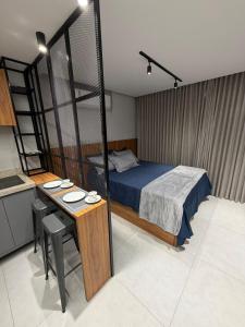 a bedroom with a bed and a desk and a bed and a kitchen at Flat mobiliado no CITY HOUSE in Barreiras