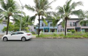 a white car parked in front of a house with palm trees at Nova Villas Phu Quoc in Phú Quốc