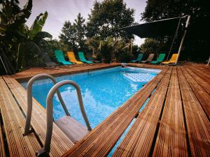 a swimming pool with chairs and a wooden deck at La Clef des Ondes in Magescq