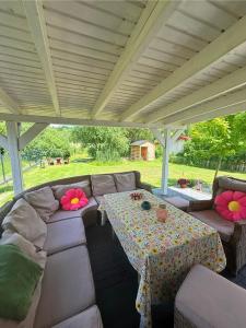a patio with a couch and a table with flowers on it at Zakątek Lechicki Domek in Tarnów Jezierny