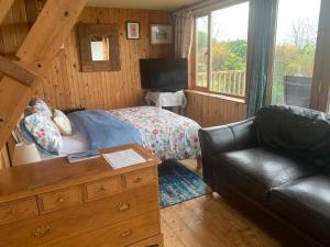 a bedroom with a bed and a couch in a room at Portlea Cabin in Oban