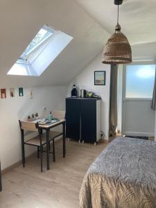 a bedroom with a bed and a table and a skylight at chambre spacieuse indépendante PDJ inclus in Plougastel-Daoulas