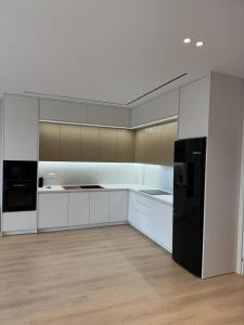a kitchen with white cabinets and a black refrigerator at Apartment 51 Luxury in Kamëz +9 photos