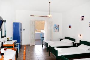 a room with two beds and a table and chairs at Litsas Studios Kythnos in Kithnos