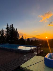 a swimming pool with a sunset in the background at котедж Квітуча Гора in Yablunytsya