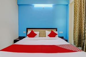 a bed with red pillows in a blue room at Hotel O Shiva Grand in Chinhat