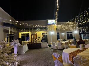 a banquet hall with white tables and chairs and lights at Katavi Empire Hotel in Mpanda