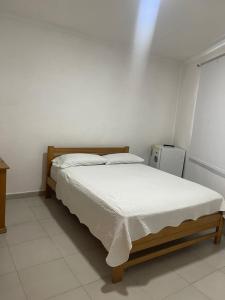 a white bedroom with a bed and a refrigerator at yasa by SEA CRAB in San Andrés
