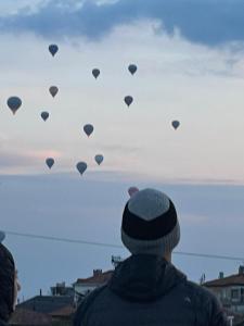 a person is looking up at a bunch of hot air balloons at Zeppelin Cappadocia in Uçhisar