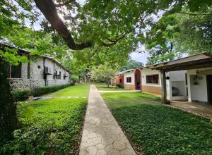 a walkway in front of a yard with two buildings at Hotel Boutique El Rosario in Teapa
